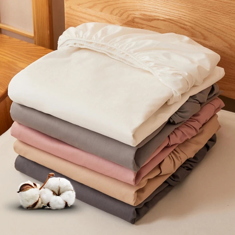 Stack of folded fabric sheets in various colors on a wooden surface.