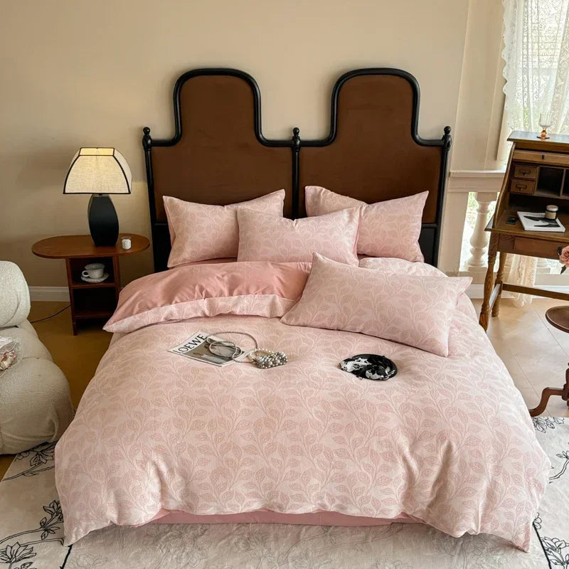 Pink floral bedspread on a bed with a wooden headboard in a bedroom setting.
