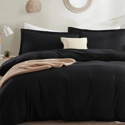 Black bedding set with beige blanket on a bed in a bedroom setting.