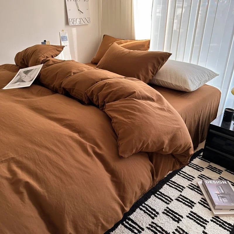 Brown bedspread on a bed with pillows in a well-lit room.