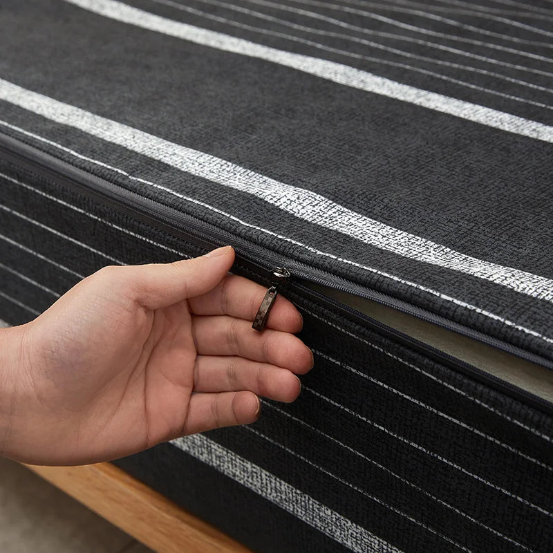 Hand holding a small object near a black and gray striped fabric surface