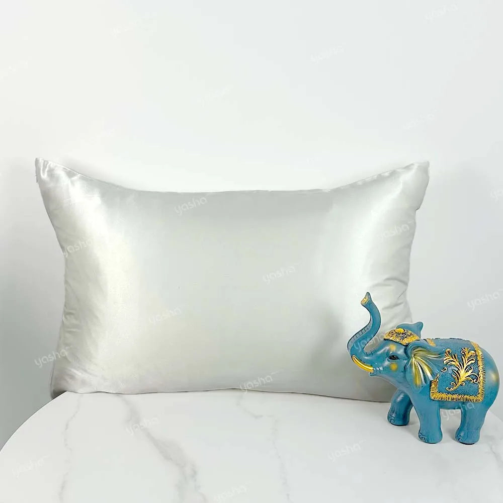 Decorative blue elephant figurine next to a satin pillow on a white background